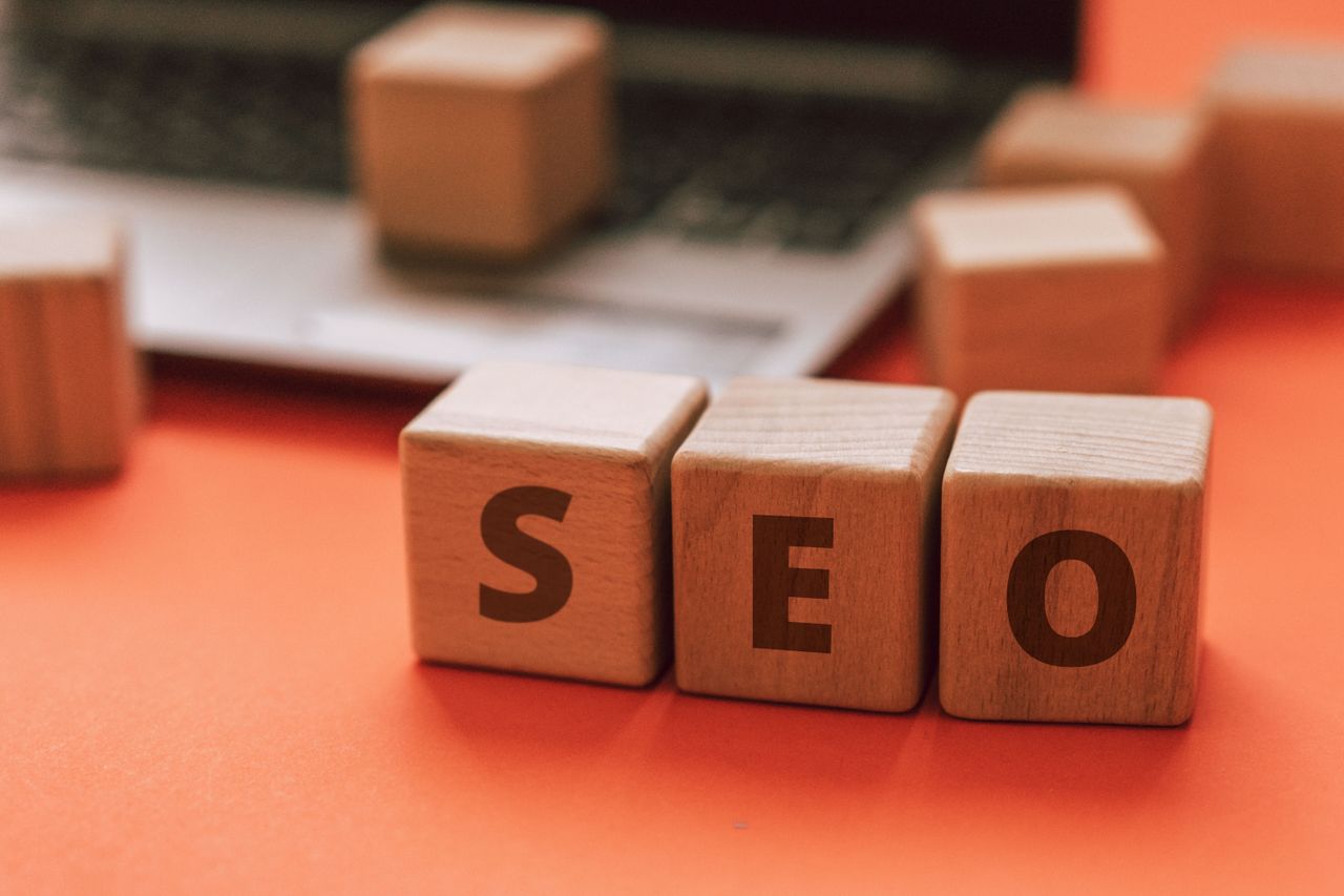 Des blocs de bois formant SEO sur le clavier d’un ordinateur portable illustrent des notions de marketing numérique.